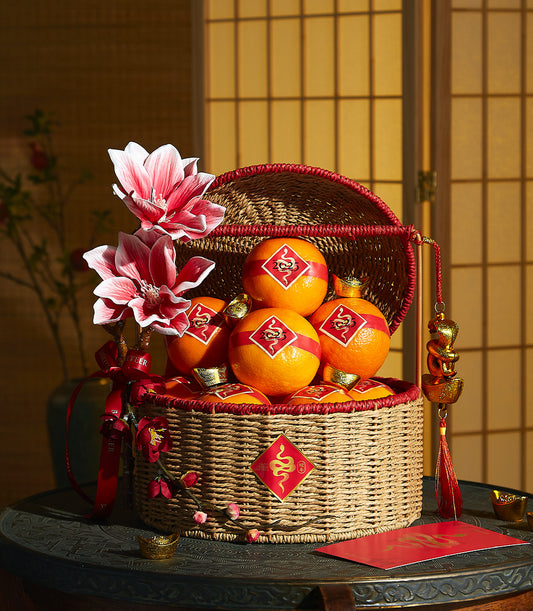 Luxury wicker gift basket with fresh mandarin oranges, red trim, and golden snake charms for Chinese New Year