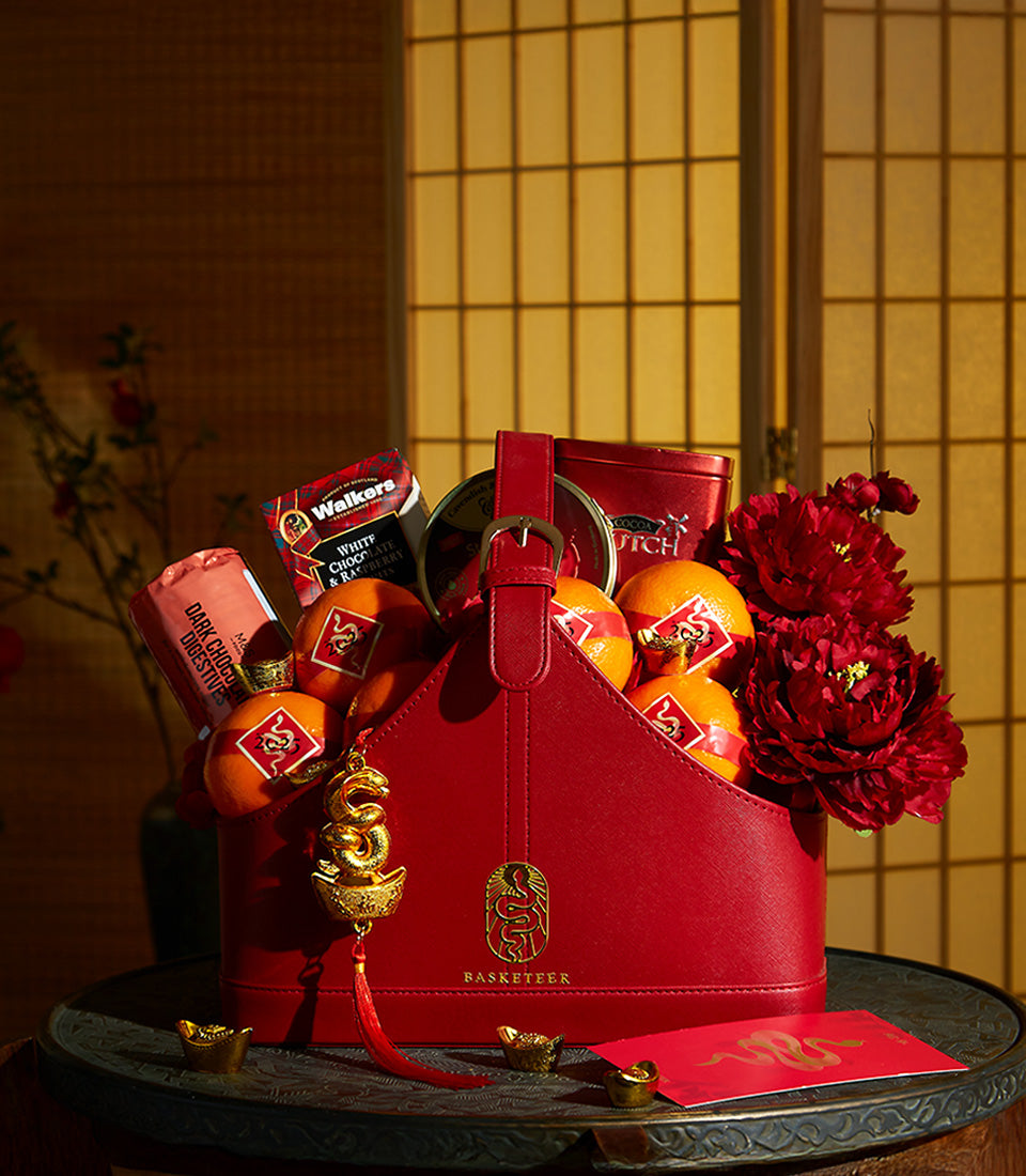 Elegant red leather gift basket filled with lucky oranges, premium biscuits, and chocolate treats for Chinese New Year