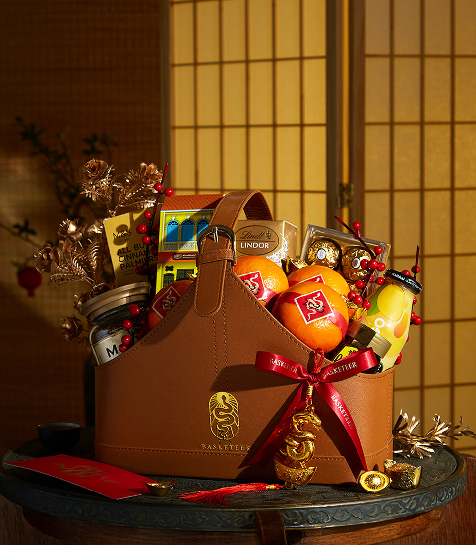 Basketeer premium hamper delivery Thailand. Elegant brown leather gift basket with oranges, Lindt chocolates, and red ribbon. Perfect corporate gift Bangkok.