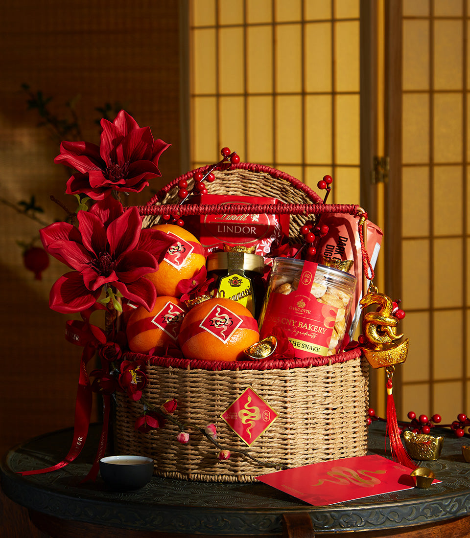 Red wicker prosperity hamper with oranges, Lindor chocolates, and festive treats for Chinese New Year