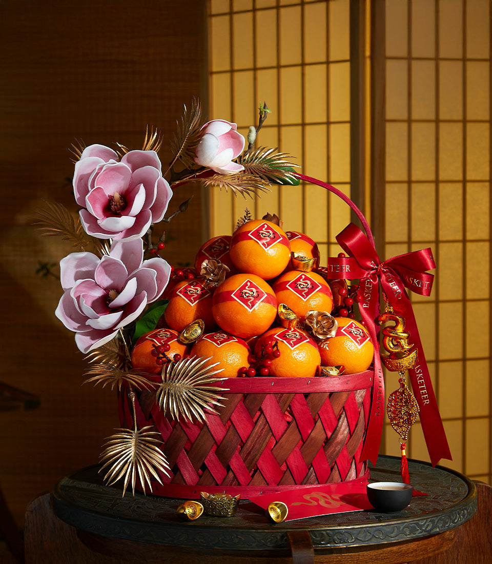 Deluxe woven red and brown basket filled with lucky oranges, gold ingots, and festive magnolia flowers for Chinese New Year