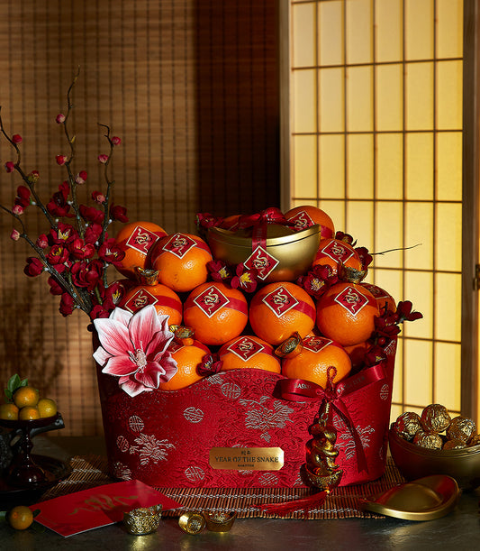 Red and gold Chinese New Year prosperity basket with mandarins, plum blossoms, and Year of the Snake ornaments