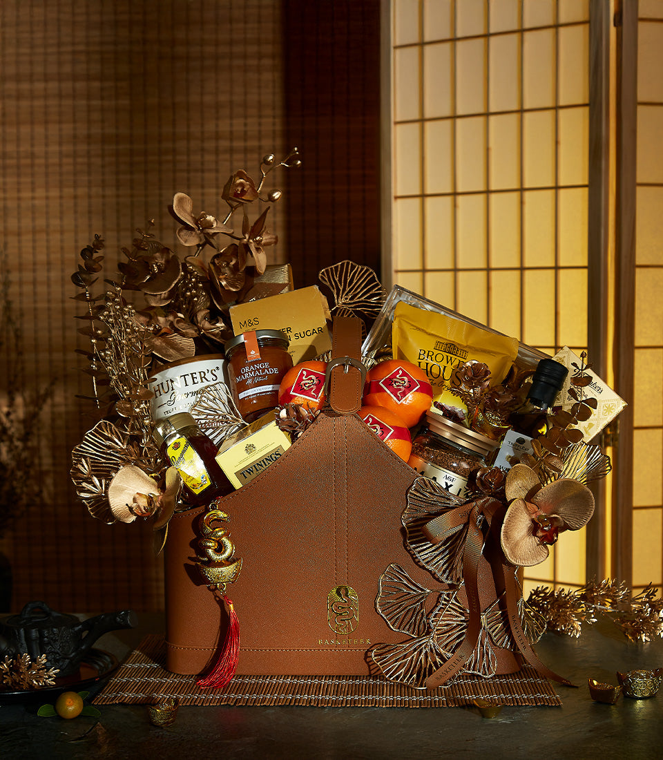 Luxury Basketeer corporate gift hamper for Chinese New Year. Premium goodies like marmalade, tea, and oranges artfully arranged in a stylish leather gift box with brown ribbon.