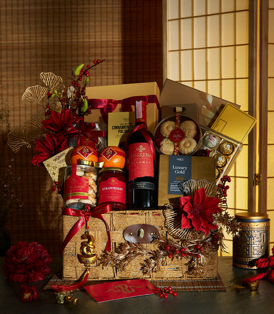 Lunar New Year luxury gift hamper with red wine, gourmet cookies, jam, and artisan chocolates in gold-accented wicker basket