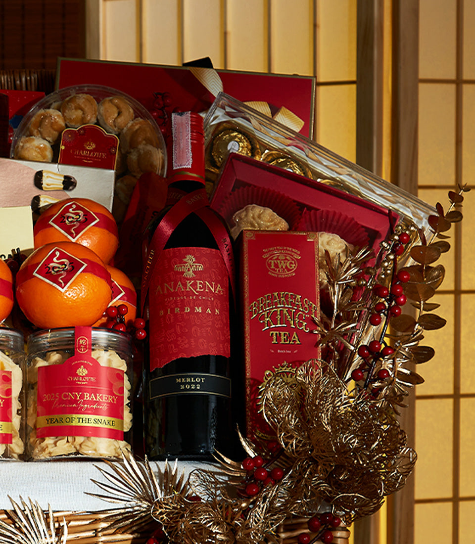 Red wine and gourmet Lunar New Year gift basket with pastries, chocolates, tea, and gold accents
