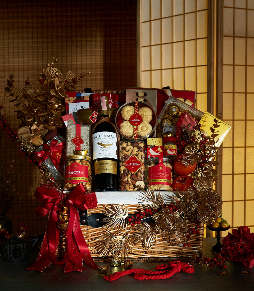 Luxury wicker gift hamper with red wine, gourmet treats, and festive gold accents for celebration gifting