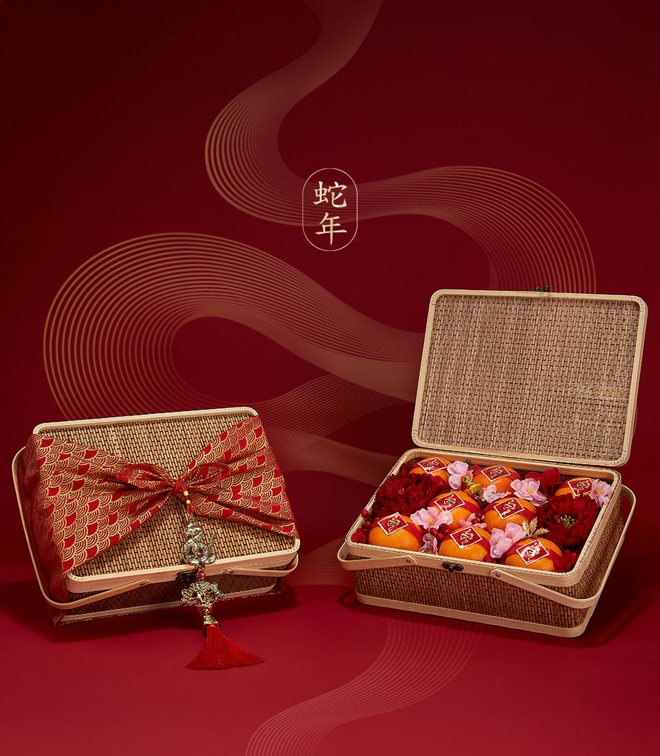 Woven bamboo gift basket with festive mandarin oranges, red peonies, and cherry blossoms for Chinese New Year