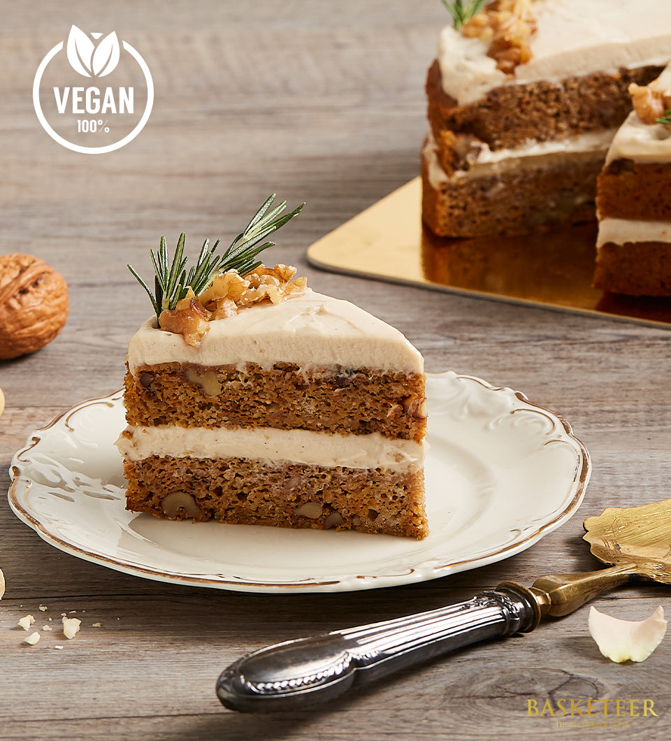 Vegan carrot cake slice with walnut frosting and fresh rosemary on gold-rimmed plate, artisan birthday cake by Charlotte