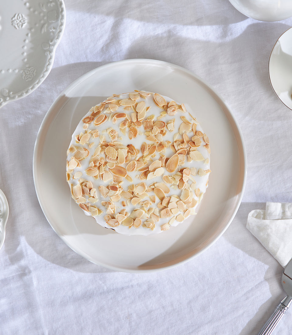 Charlotte Bakery Cherry Bakewell almond cake with white icing and toasted almond topping on beige plate