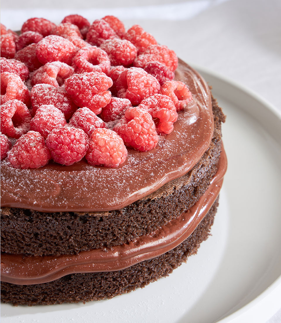 Chocolate Raspberry Ganache celebration cake with fresh raspberries and powdered sugar
