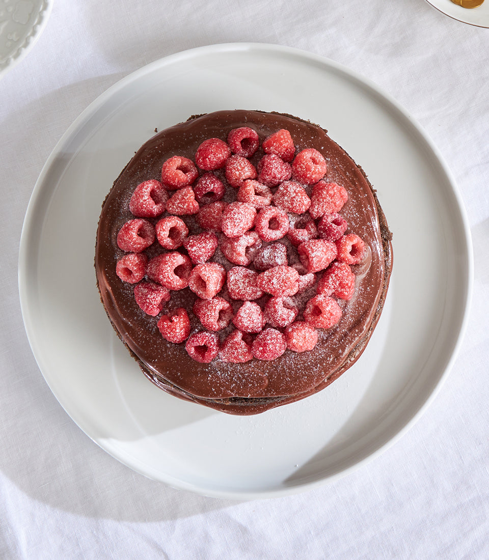 Dark chocolate ganache cake with fresh raspberries and powdered sugar, artisan celebration cake by Charlotte Bakery