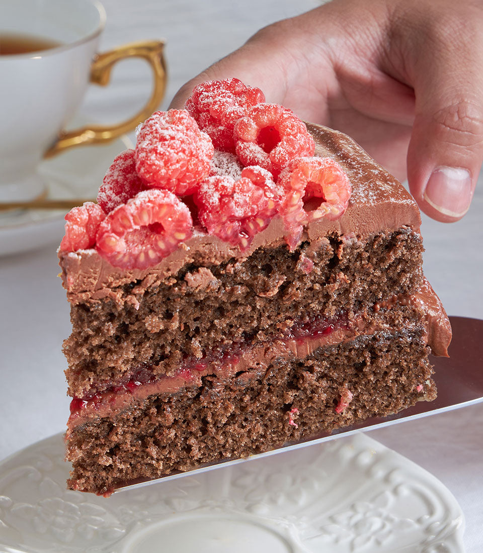 Dark chocolate layer cake with raspberry ganache and fresh raspberries on embossed plate