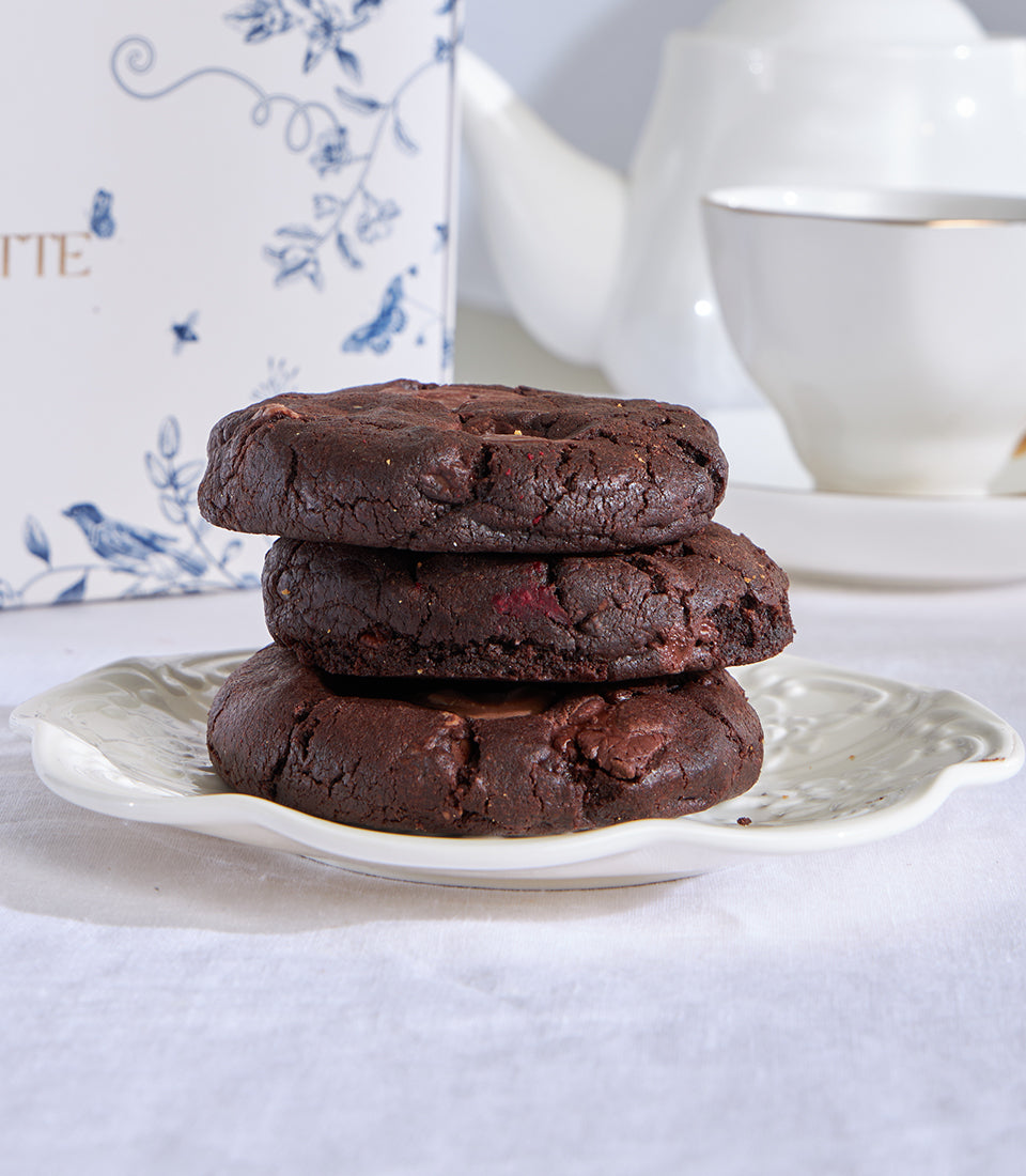 Dark chocolate chip cookies with cranberry pieces stacked on decorative plate, artisan bakery gift set