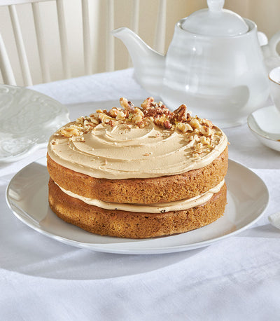 Two-layer coffee walnut cake with gold leaf topping on ceramic plate, artisan bakery gift