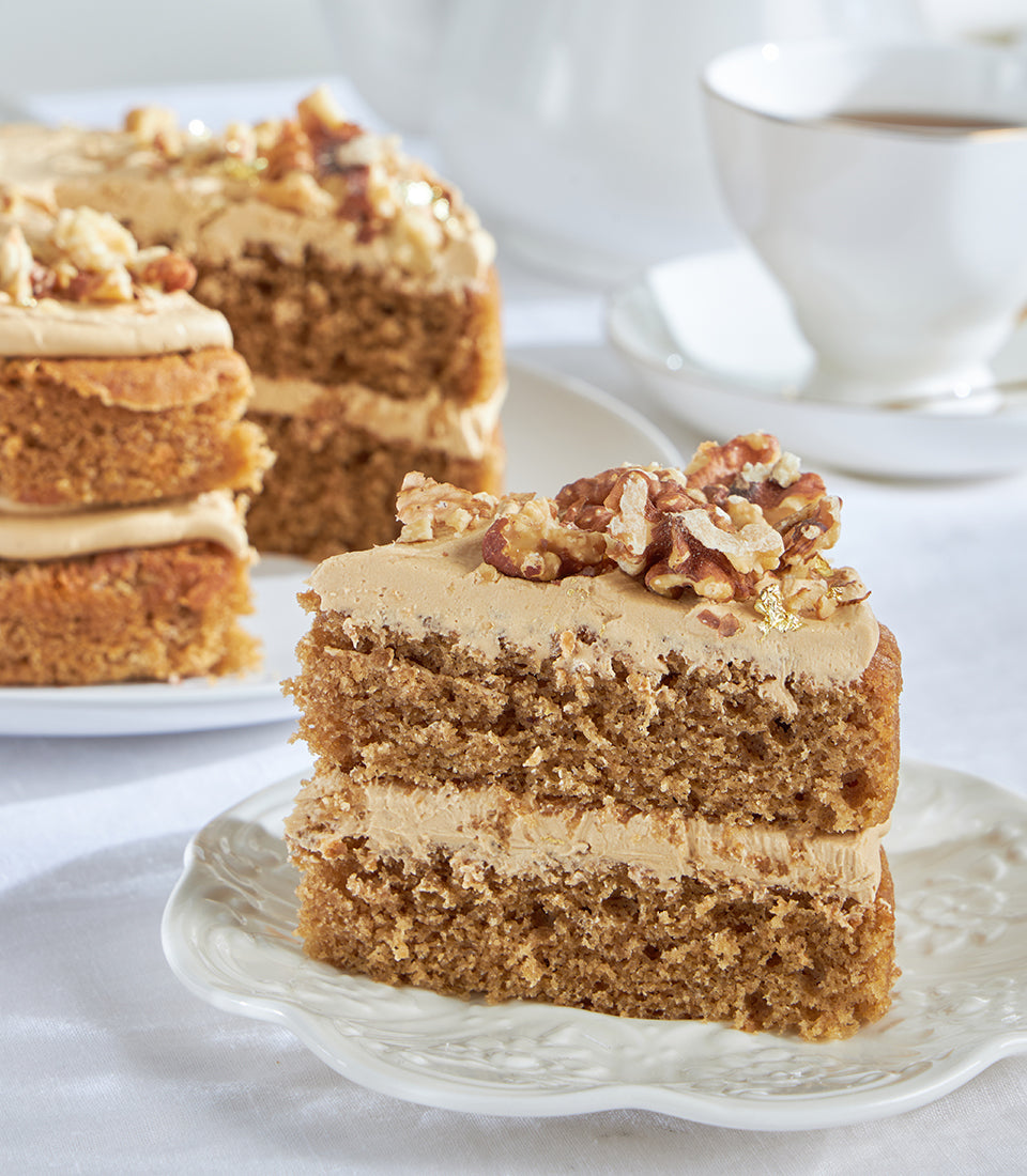 Coffee and walnut cake slice with gold leaf on scalloped plate, elegant tea-time setting