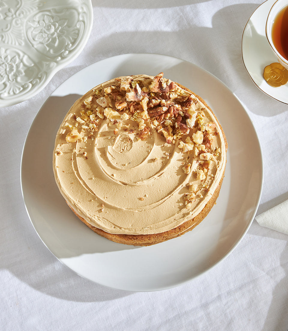 Sue's Classic Coffee & Walnut Cake with light brown frosting, walnuts and gold leaf, served with tea