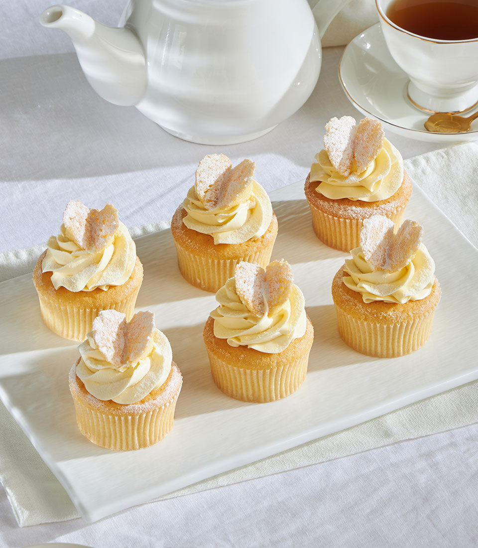 Frosted vanilla cupcakes with butterfly decorations and swirled icing on white platter, Charlotte Bakery signature design