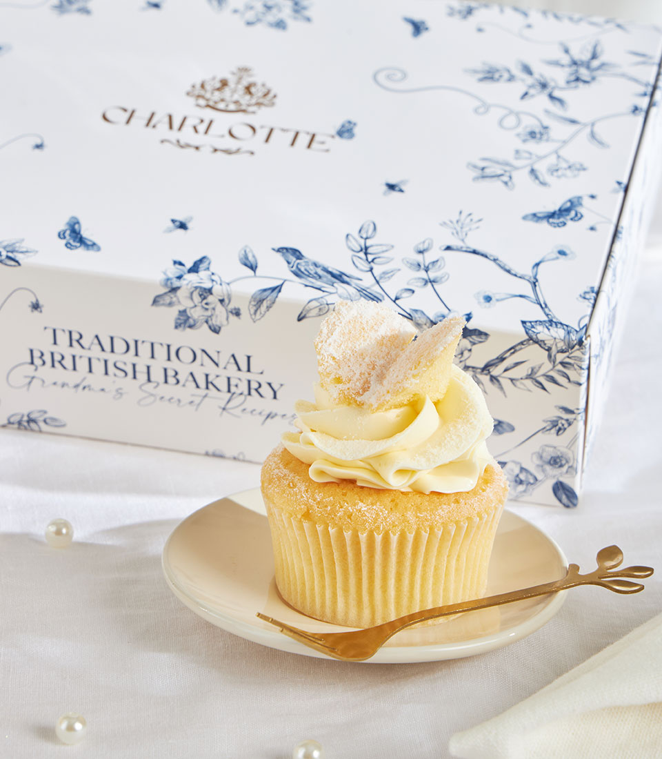 White frosted vanilla cupcake with sugar butterfly and gold leaf fork on cream saucer, British bakery gift