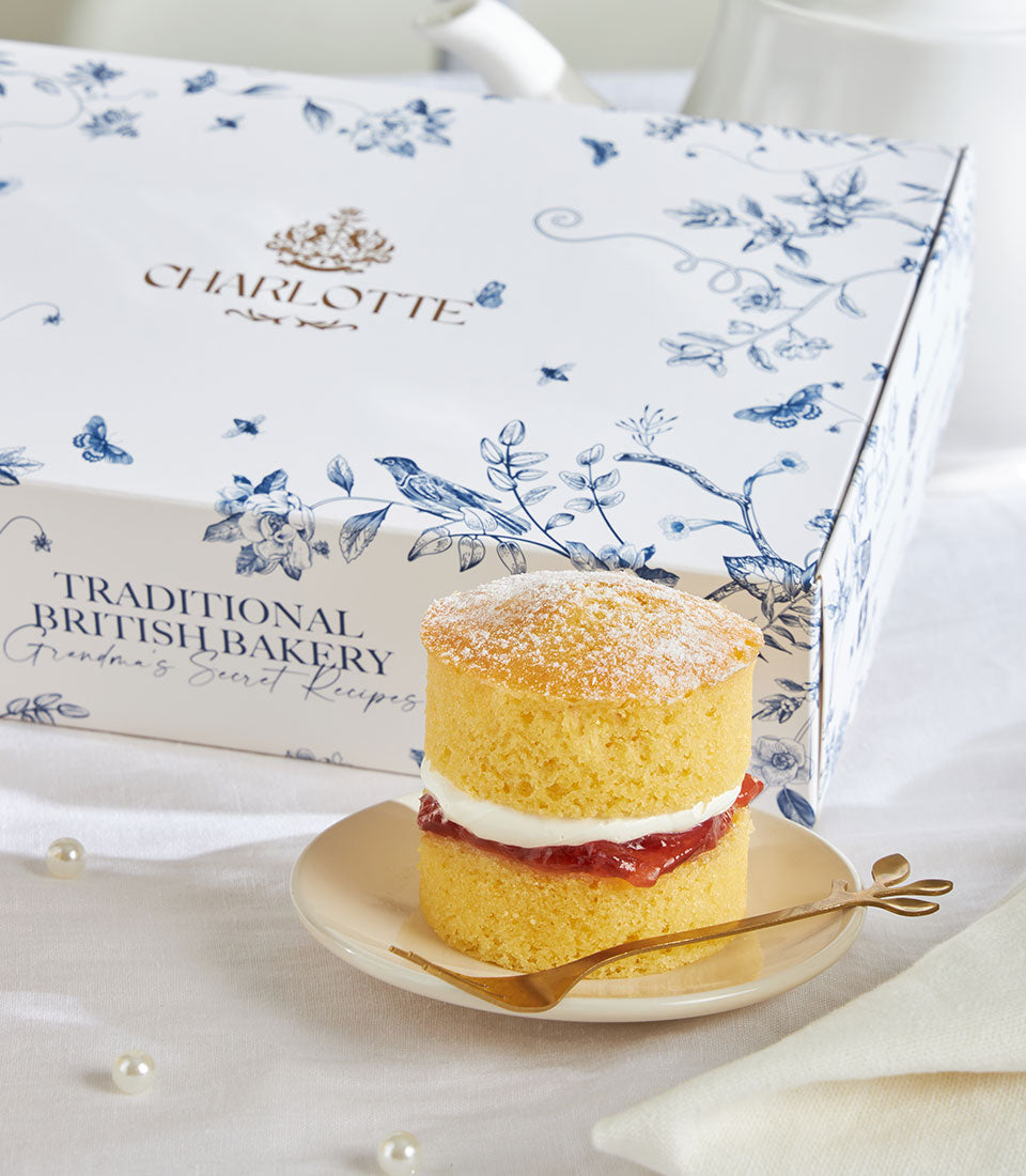 Mini Victoria sponge cake with jam and cream, dusted with powdered sugar, served with gold fork