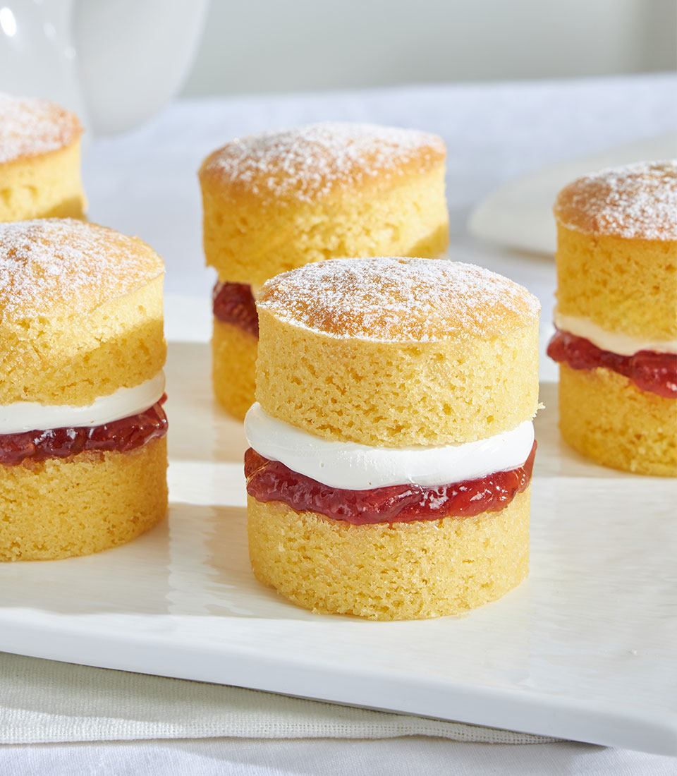 Mini Victoria sponge cakes with jam and cream, dusted with powdered sugar