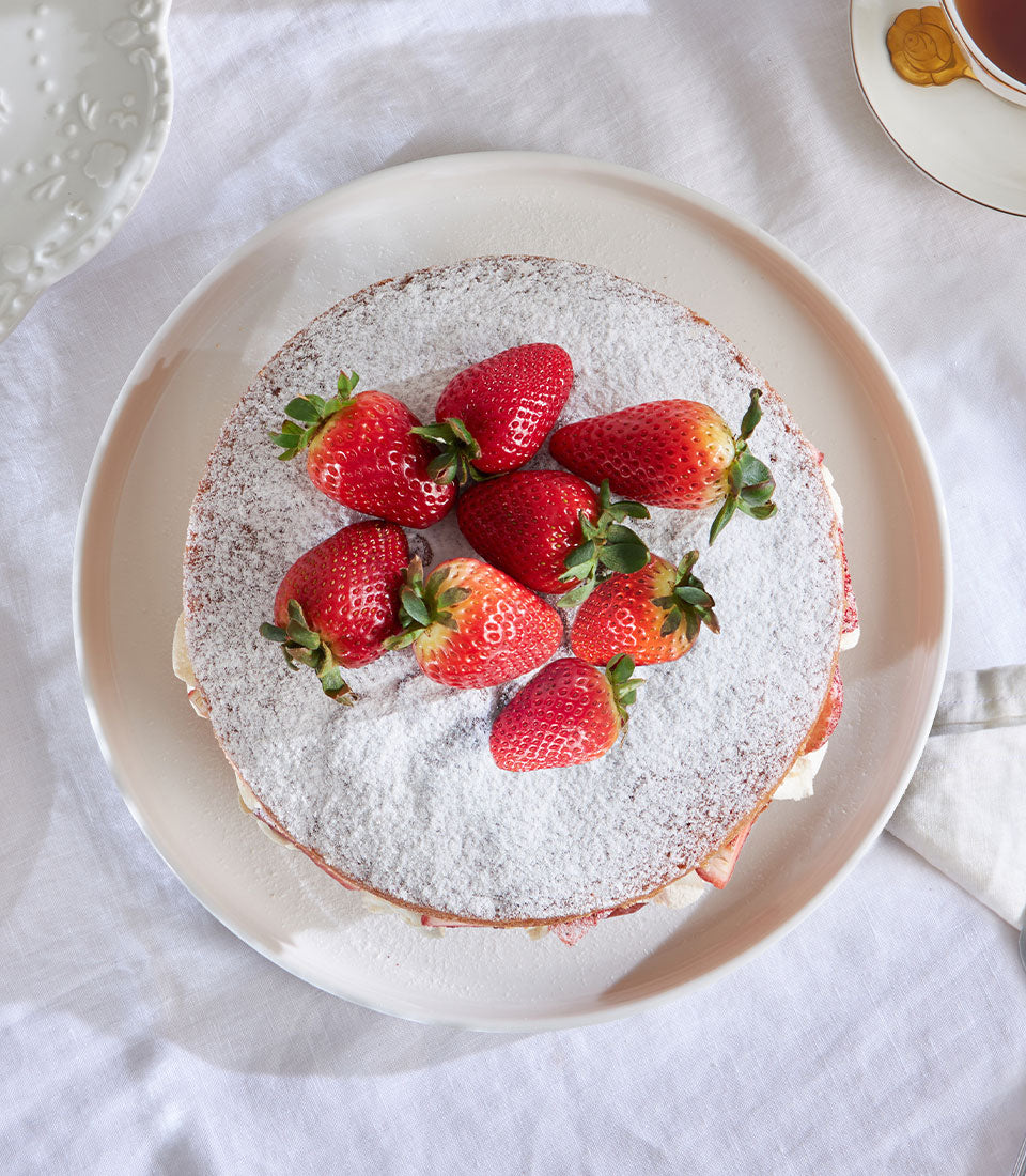 Thai strawberry Victoria sponge cake with powdered sugar and fresh berries, artisan birthday celebration cake