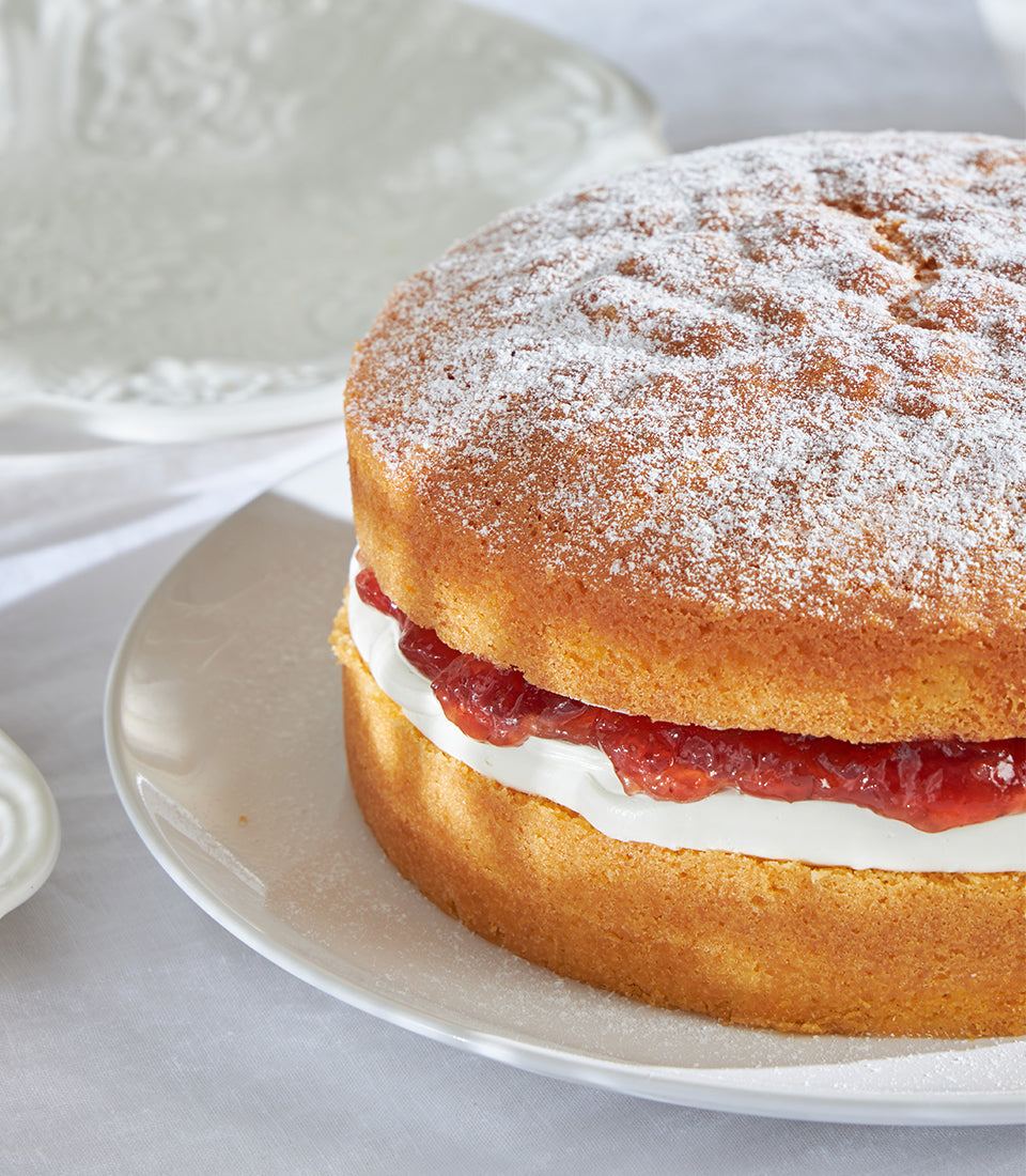 Classic Victoria sponge cake with jam and cream filling, dusted with powdered sugar