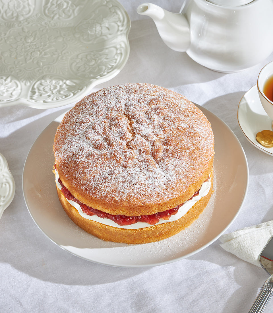 Classic Victoria sponge cake with jam and cream filling, dusted with powdered sugar, British-style celebration cake