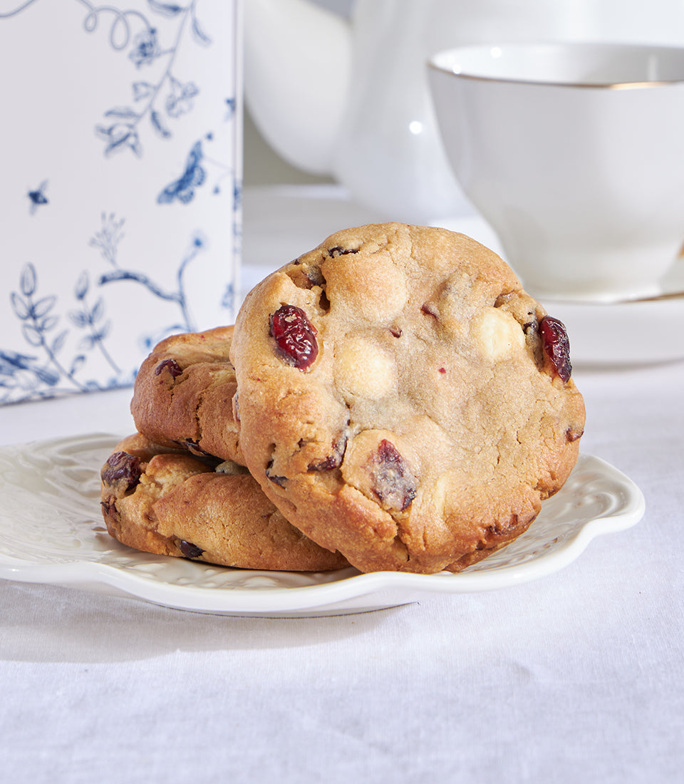 White chocolate macadamia and red velvet cookies on scalloped plate with teacup setting