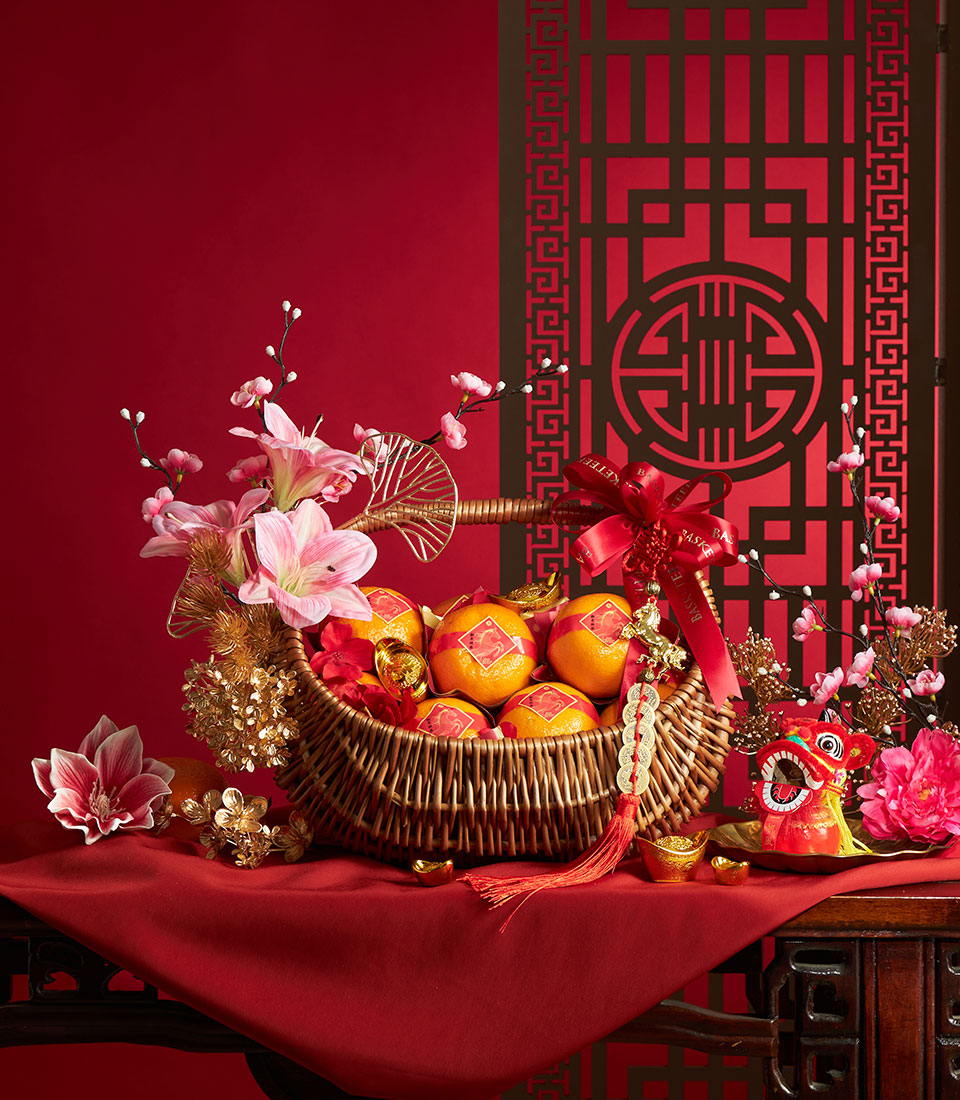 Woven wicker basket of 12 Taiwan mandarin oranges with red gold-character bands, red ribbon bow, and lucky charms for