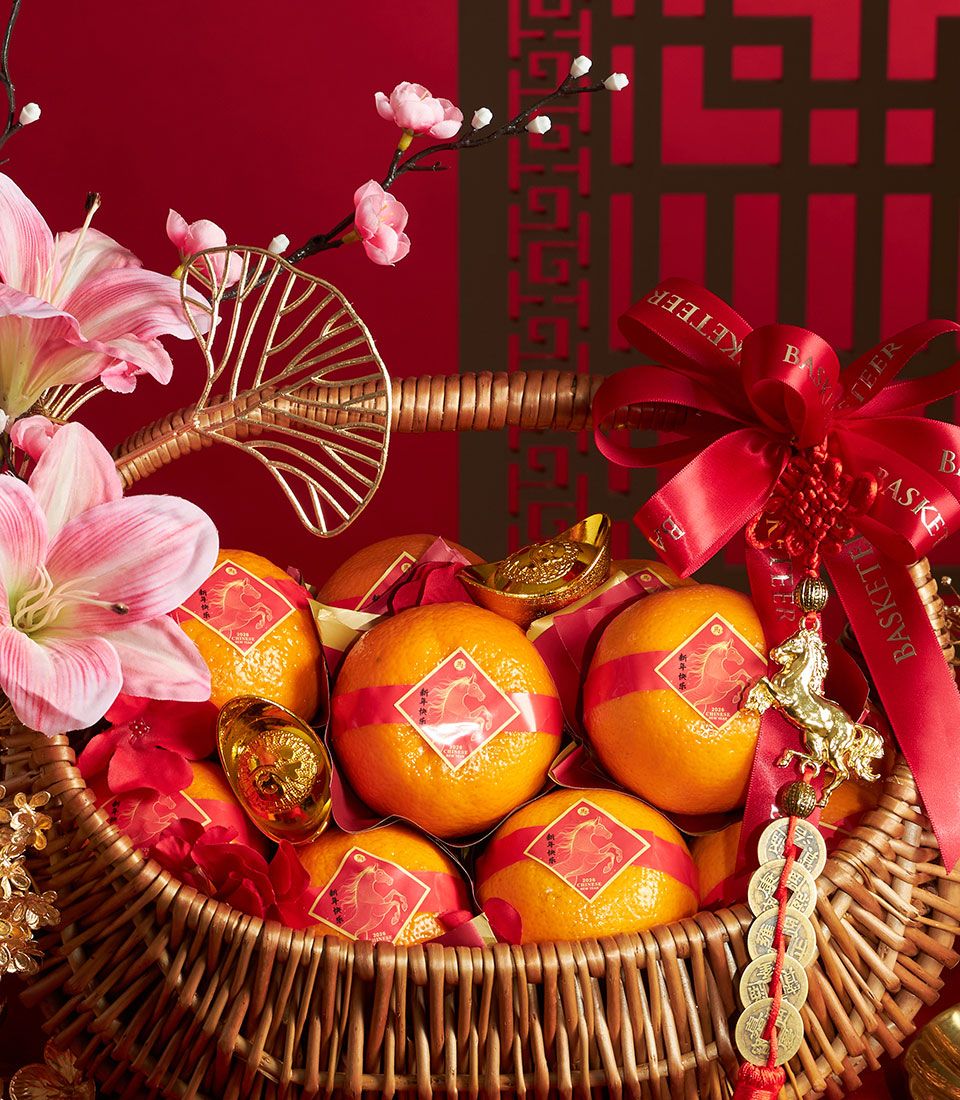 Mandarin orange gift basket with red satin bow, gold ingots, and Chinese New Year horse charms for festive gifting