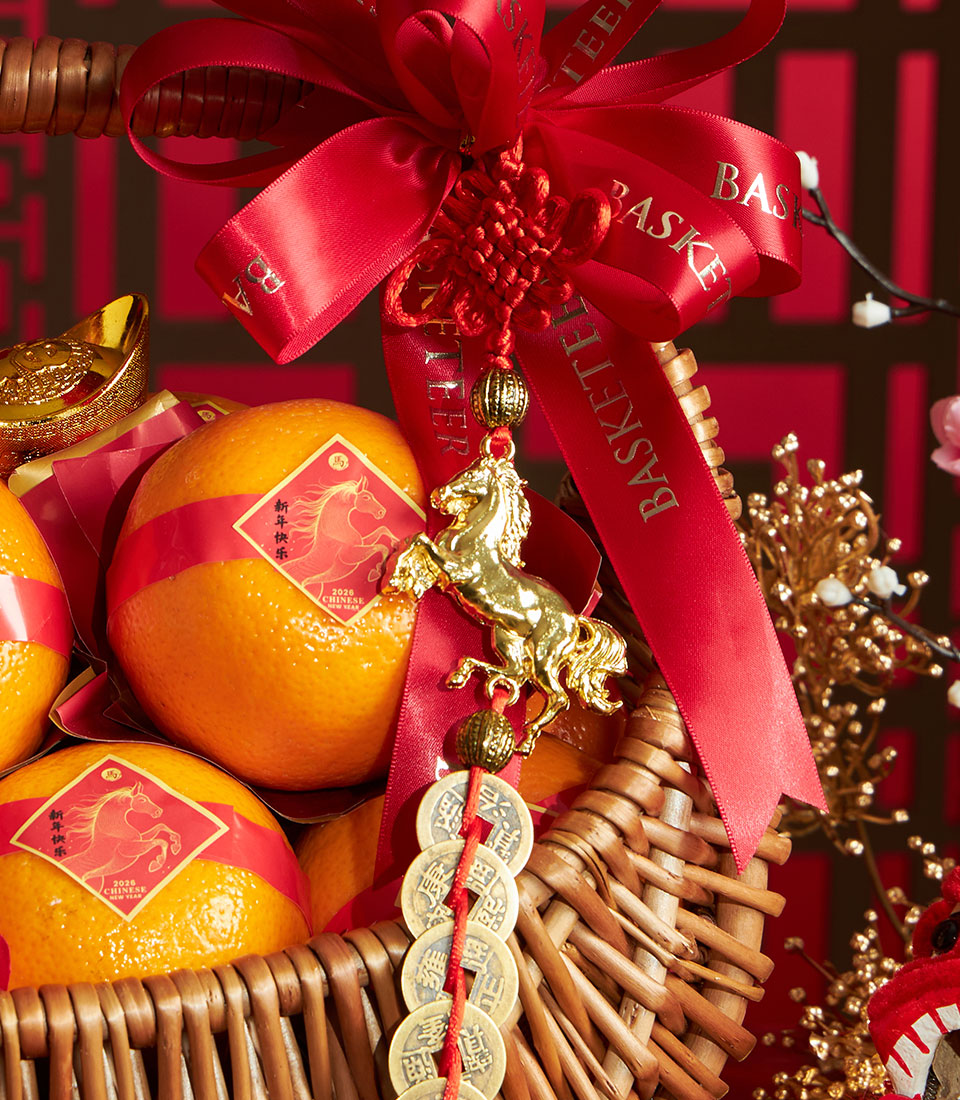 Festive mandarin orange gift basket with red silk ribbons, gold horse charms, and woven wicker for Chinese New Year