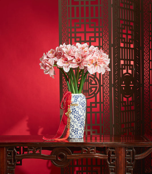 Basketeer Chinese New Year gift: Artificial amaryllis arrangement in blue and white vase with red ribbon detail. Premium floral Bangkok delivery.