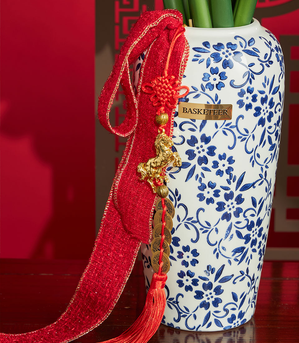 Basketeer luxury gift: Artificial amaryllis in a blue & white vase, adorned with a red ribbon, lucky coins and a golden horse for a prosperous Chinese New Year.