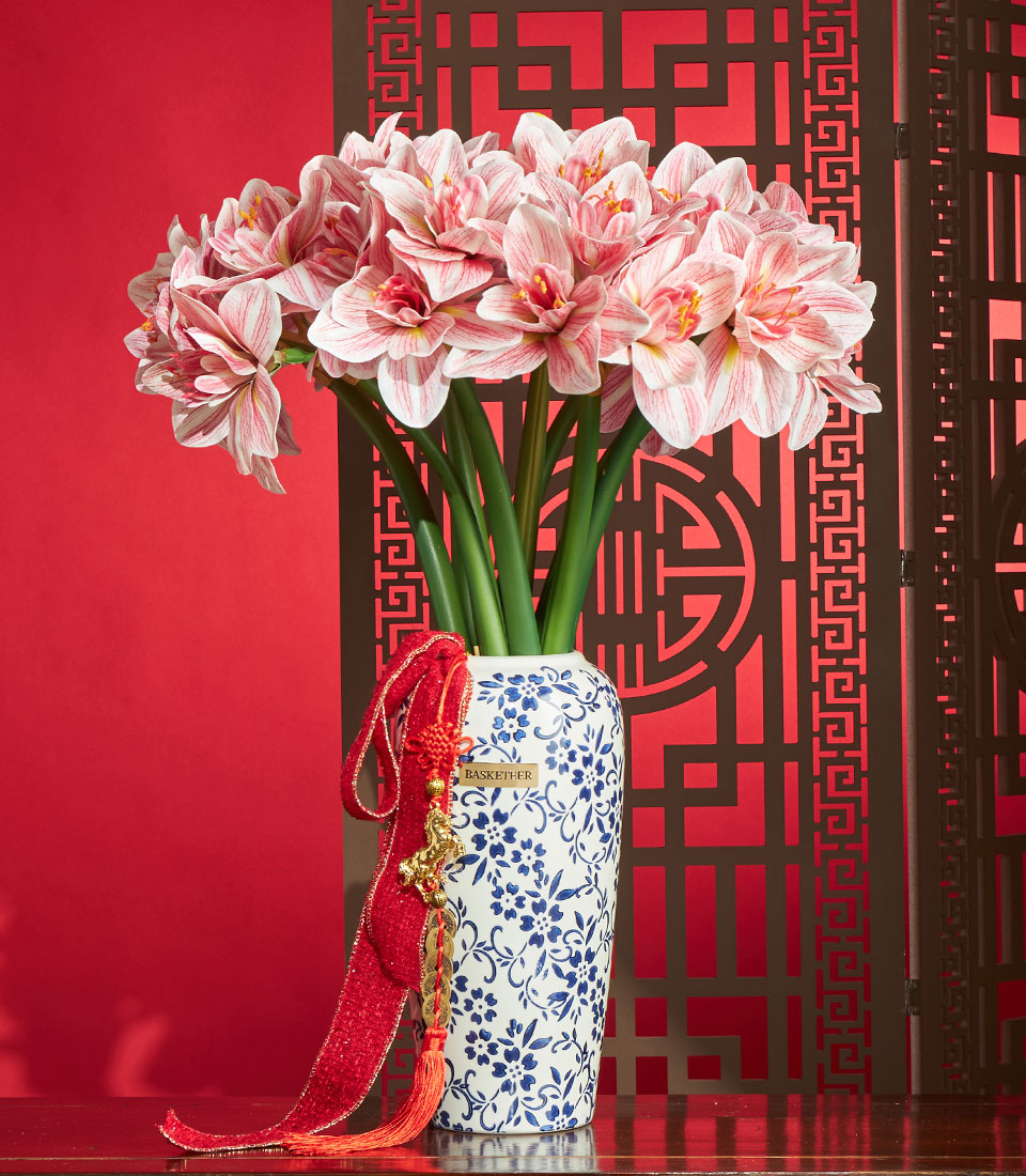 Basketeer artificial amaryllis flower arrangement in blue-and-white vase, a premium gift for Chinese New Year in Bangkok. Red and gold tassel detail.