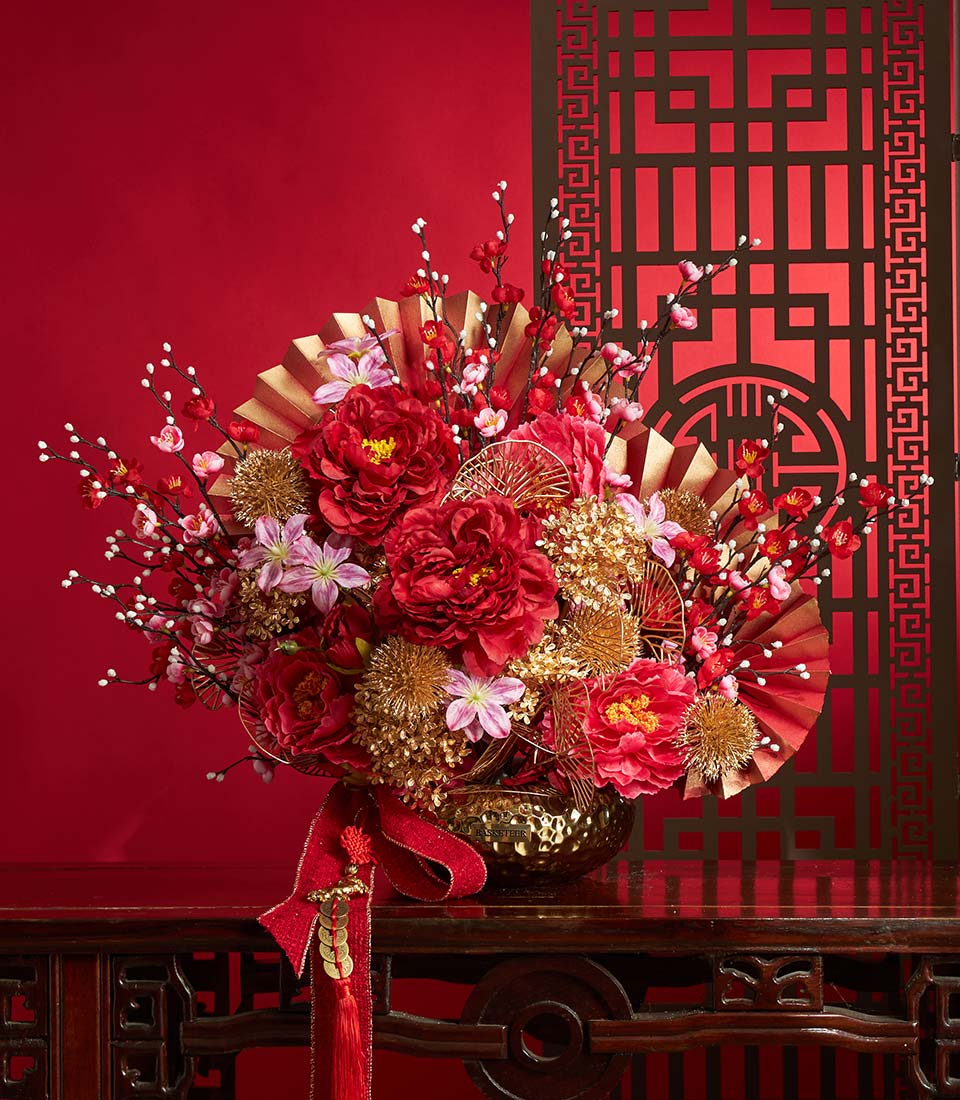 Basketeer premium floral gift: Peony & cherry blossom arrangement with gold accents and red ribbon. Perfect corporate gift for Chinese New Year in Bangkok.