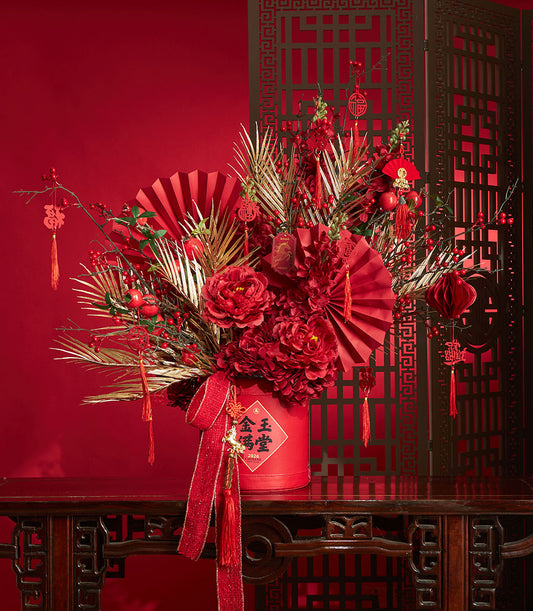 Basketeer premium hamper delivery Thailand: Red and gold floral arrangement with peonies, decorative fans, and festive hanging ornaments. Elegant corporate gift Bangkok.