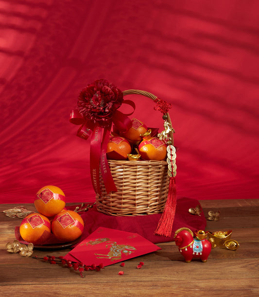 Festive Chinese New Year mandarin orange gift basket with red ribbon, gold accents, and lucky decorations on red background