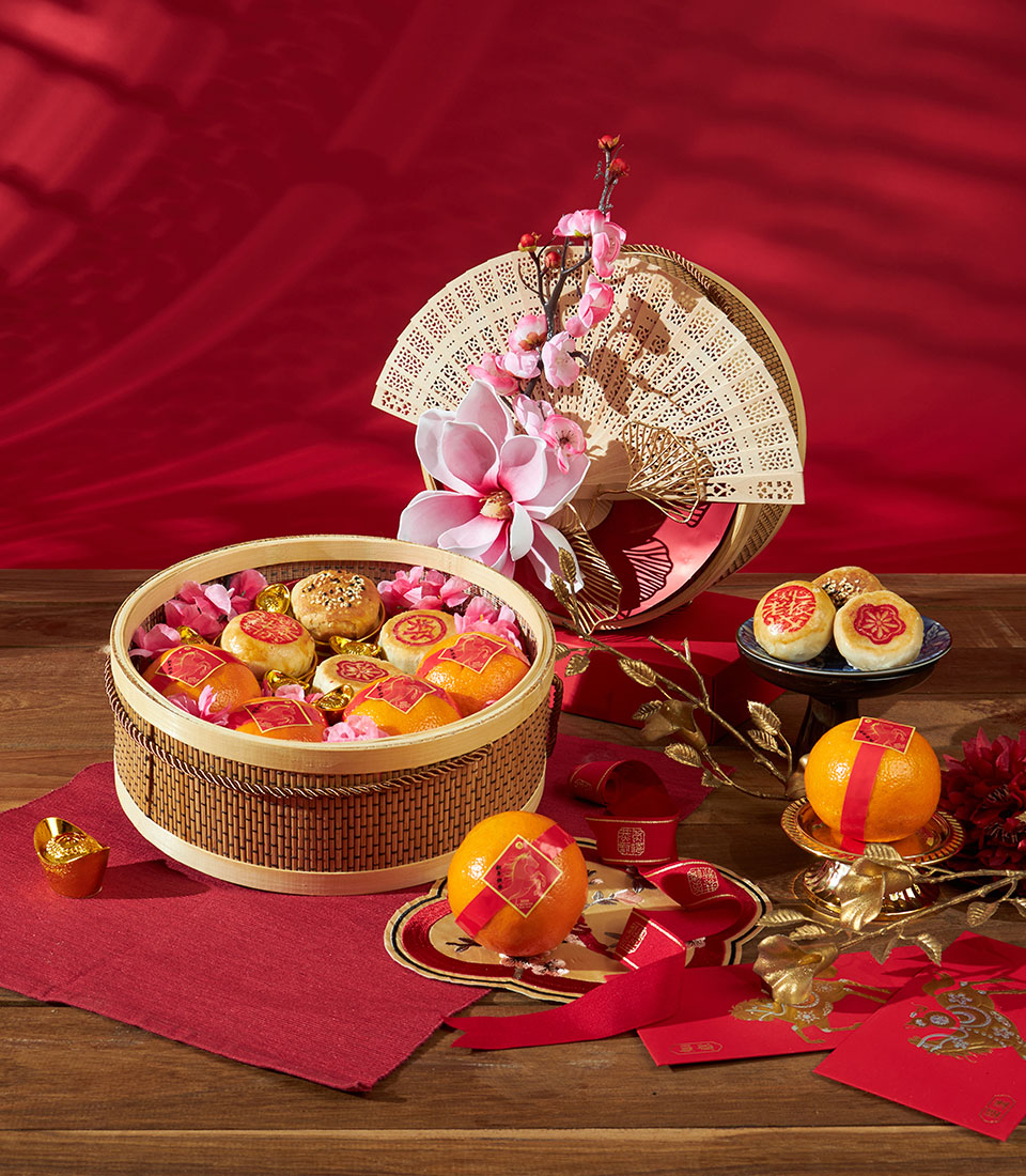 Festive mandarin oranges and pastry gift basket with red and gold accents for Chinese New Year celebrations