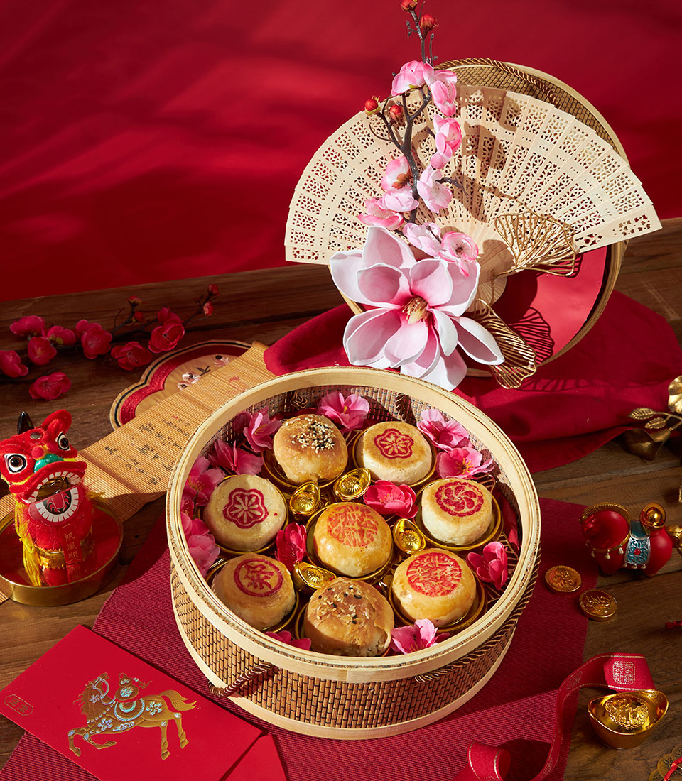 Festive Chinese pastry gift box with bamboo steamer, red envelopes, and lion dance décor for Lunar New Year