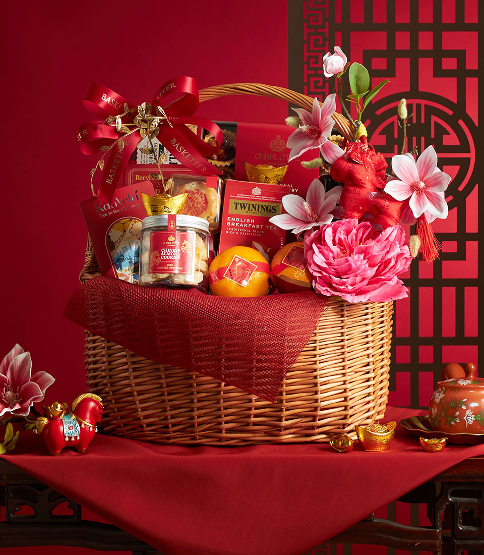 Festive wicker gift basket filled with mandarin oranges, almond cookies, and tea for Chinese New Year celebration