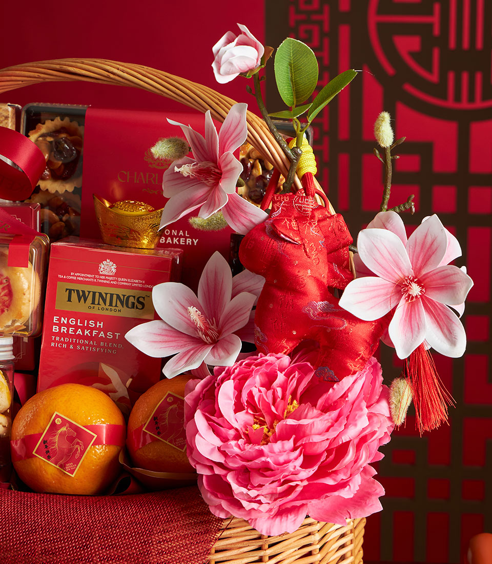 Red wicker gift basket with mandarin oranges, Charlotte Bakery pastries, Twinings tea, and golden horse ornaments for