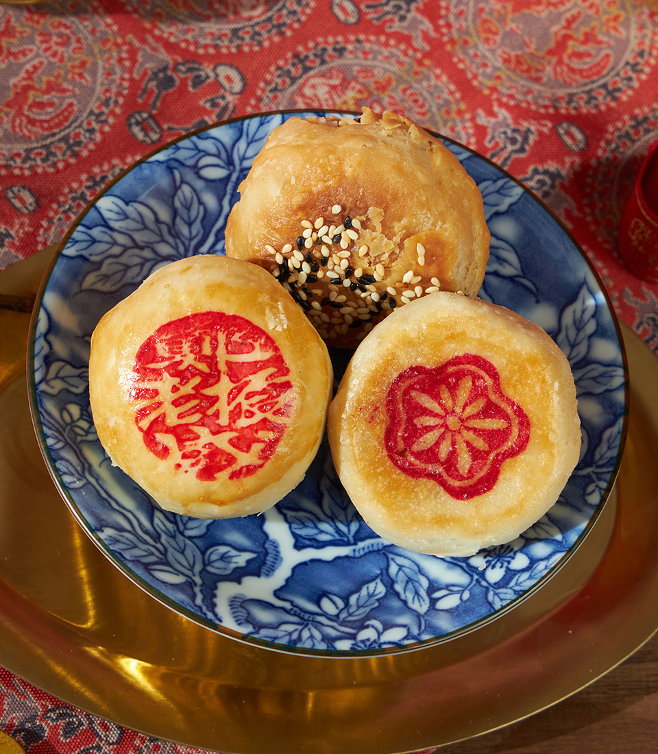 Mandarin orange pastries with red happiness character and sesame seed toppings on blue porcelain, Chinese New Year gift set