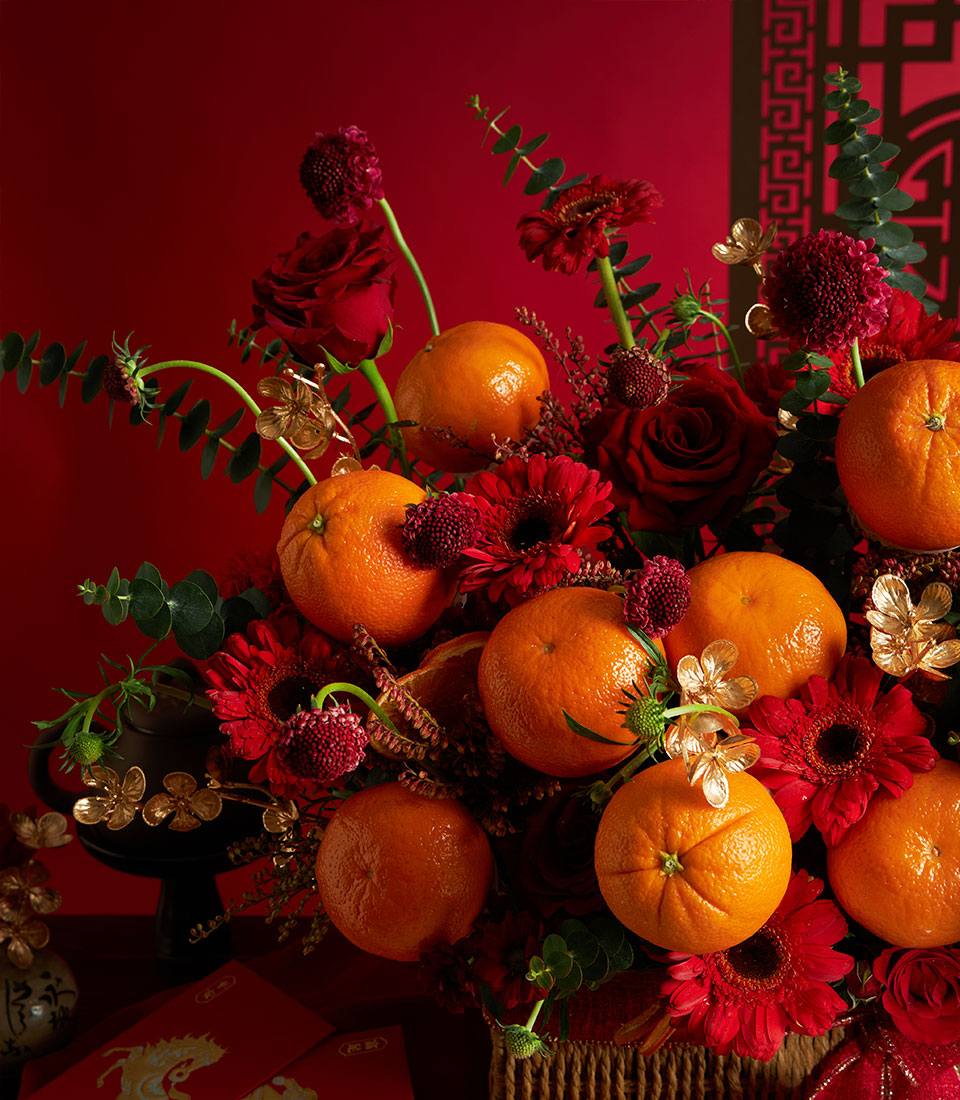 Vibrant mandarin orange and red rose gift basket with gold accents for Chinese New Year celebration