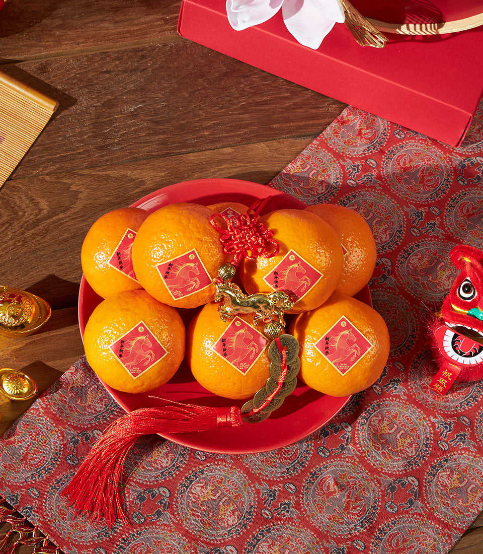 Premium mandarin orange gift set with lucky red plate, golden horse charms, and traditional Chinese New Year decorations for