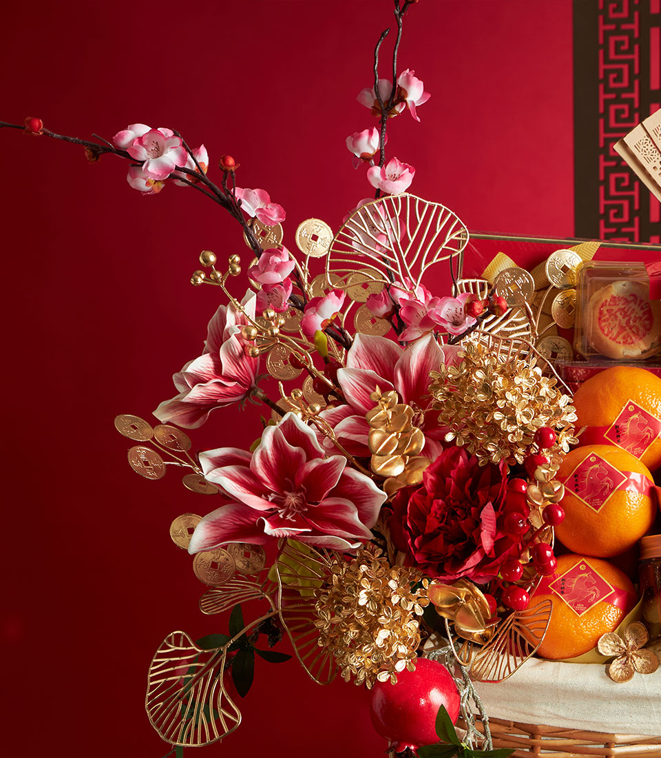Luxury Chinese New Year gift hamper with red and gold florals, mandarins, and pastries in woven basket