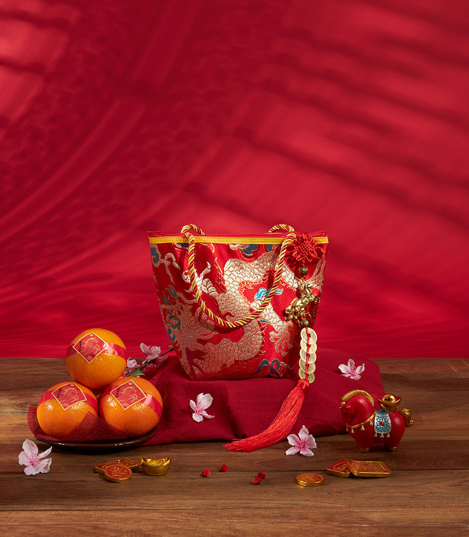 Luxury red silk gift bag with gold dragon embroidery, mandarin oranges, and festive charms for Chinese New Year celebrations