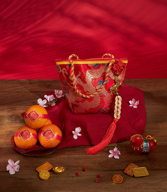 Premium red silk gift bag with gold dragon motif, mandarin oranges, and lucky charms for Chinese New Year celebrations