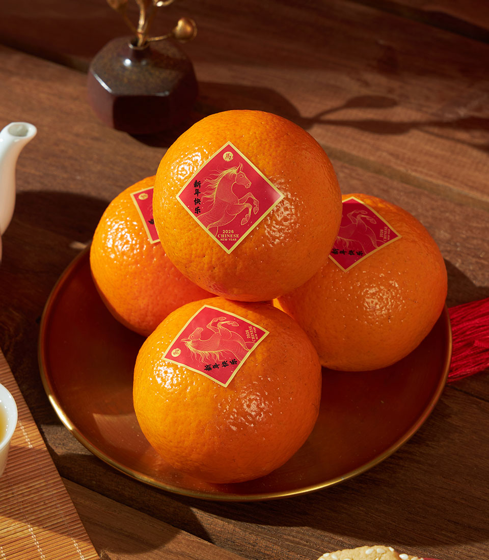 Vibrant mandarin oranges with gold lucky stickers on bronze tray, Charlotte Bakery Chinese New Year gift box