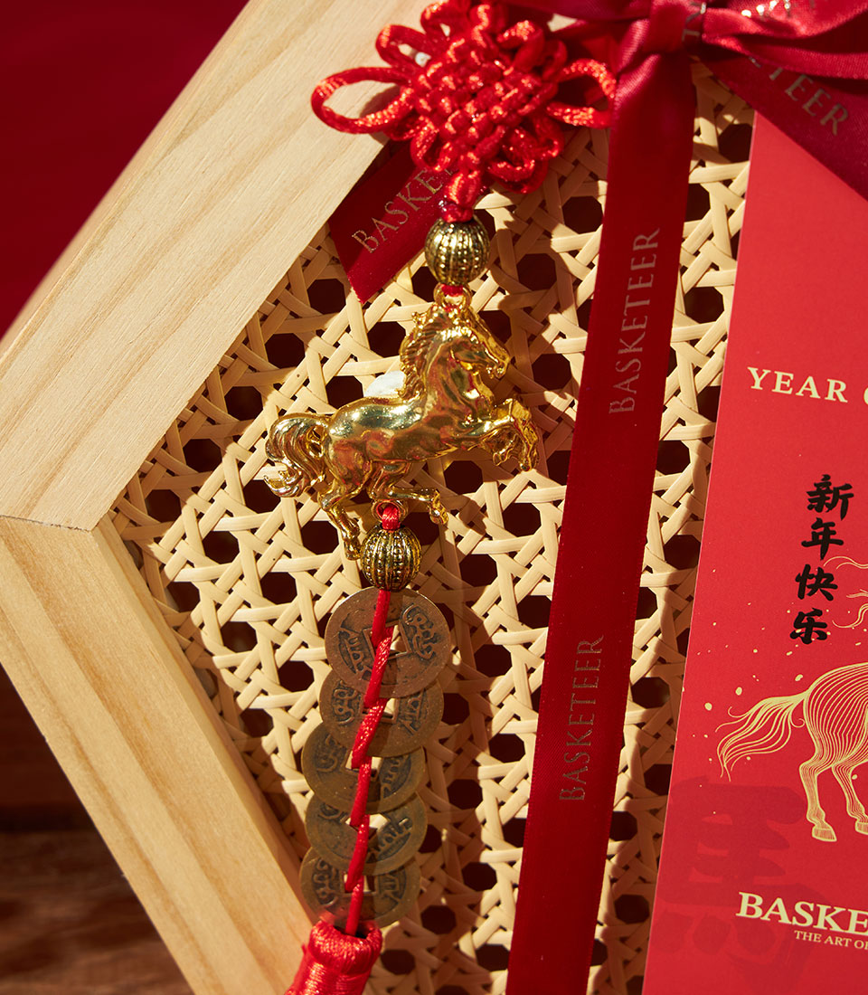 Festive Chinese New Year wooden gift box with rattan panel, red ribbon, golden horse charm, and Charlotte Bakery treats