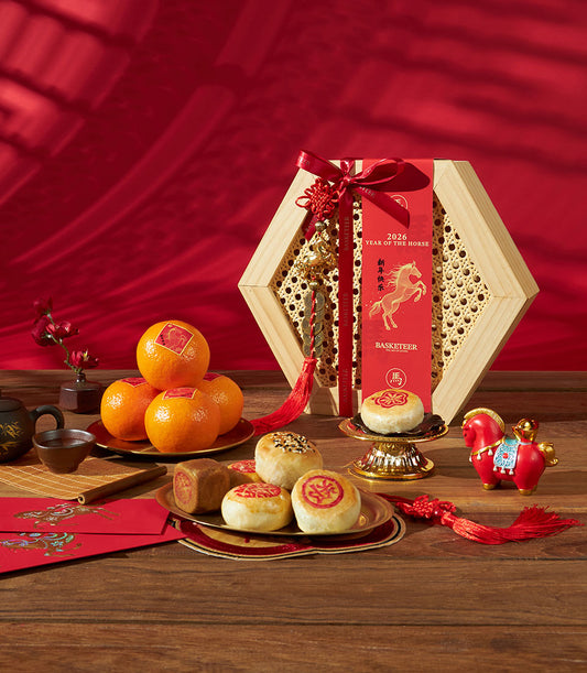 Hexagonal wooden gift box with mandarin oranges, sesame pastries, and Year of the Horse charm on red festive backdrop